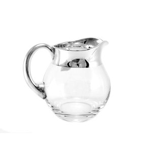 Könnte beinhalten: Ein klarer Glaskrug mit rundem Körper und silberfarbenem Rand und Griff. Der Krug hat einen gebogenen Ausguss und ein schlichtes, elegantes Design, das sich zum Servieren von Getränken eignet.