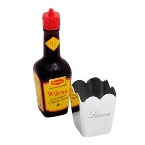 Könnte beinhalten: Eine rote und gelbe Flasche Maggi Würze mit einem silbernen Metallbehälter, auf dem der Name Laura eingraviert ist.