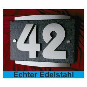 Könnte beinhalten: Ein schwarzes Schiefer-Hausnummernschild mit der Nummer 42 in weißem Metall. Das Schild hat einen silbernen Rand und ist mit "Echter Edelstahl" beschriftet, was im Deutschen "Echter Edelstahl" bedeutet.