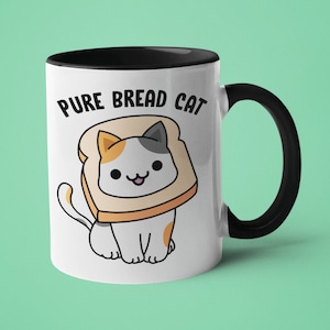 Puede incluir: Taza de cerámica blanca con borde y asa negros. La taza presenta un gato de dibujos animados que lleva una rebanada de pan como sombrero. El texto "PURE BREAD CAT" está impreso en la taza.