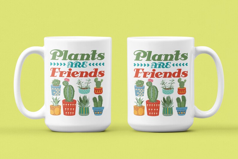 May include: Two white ceramic mugs with a green, red, and blue design of potted plants and the text "Plants are Friends".
