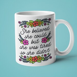 May include: White ceramic mug with a floral border and the text "She believed she could but she was tired so she didn't".