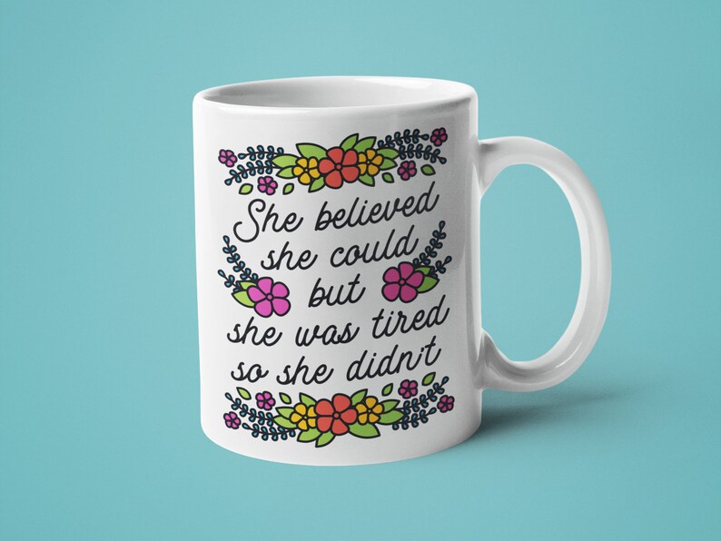 May include: White ceramic mug with a floral border and the text "She believed she could but she was tired so she didn't".