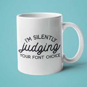 Puede incluir: Taza de caf&eacute; de cer&aacute;mica blanca con texto negro que dice "Estoy juzgando silenciosamente tu elecci&oacute;n de fuente".