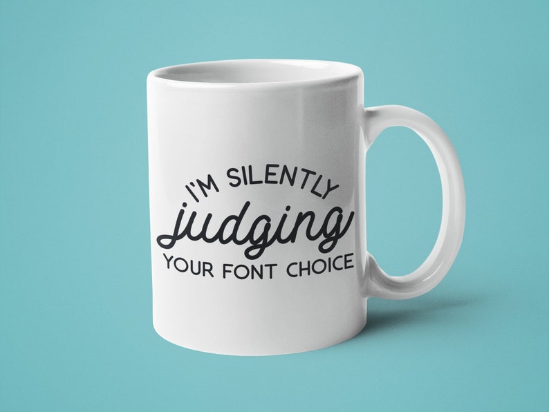 Puede incluir: Taza de caf&eacute; de cer&aacute;mica blanca con texto negro que dice "Estoy juzgando silenciosamente tu elecci&oacute;n de fuente".