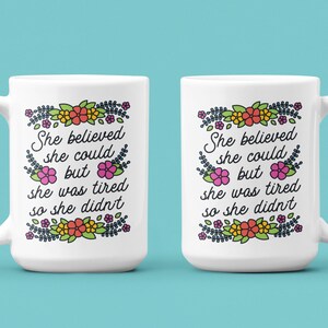 May include: Two white ceramic mugs with a floral design and the text "She believed she could but she was tired so she didn't".