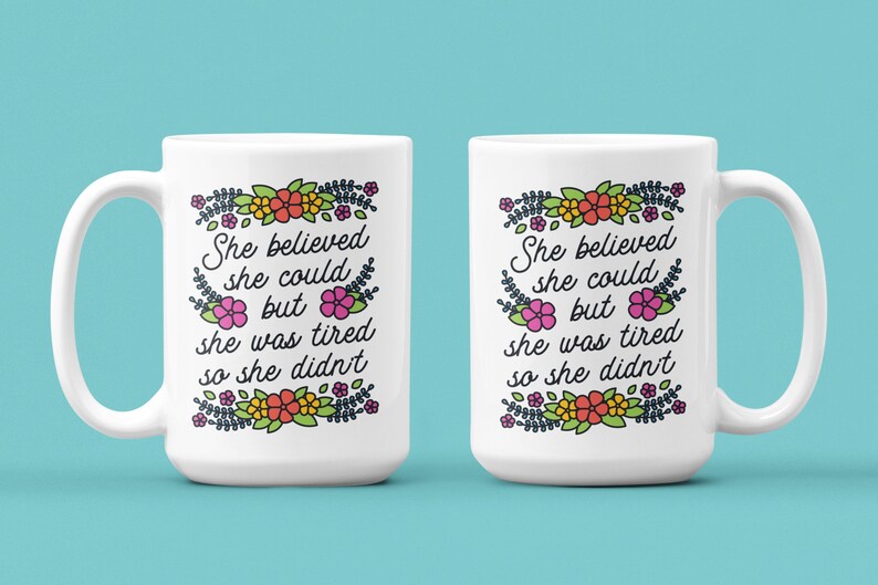 May include: Two white ceramic mugs with a floral design and the text "She believed she could but she was tired so she didn't".