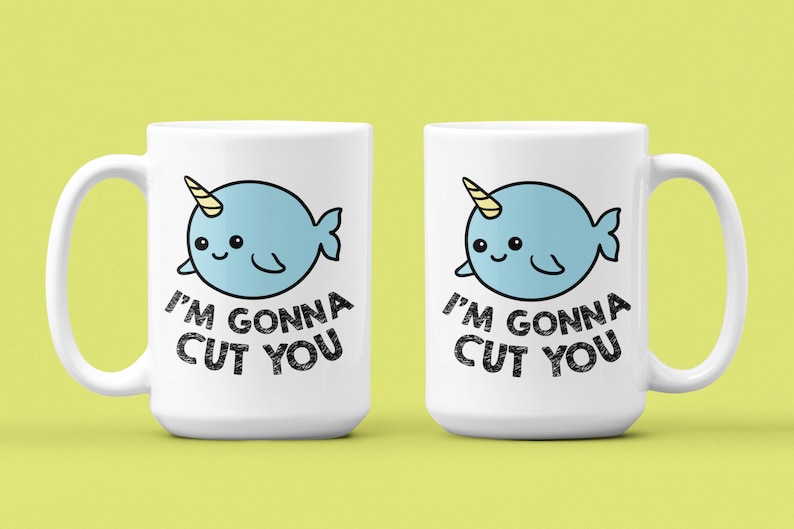 May include: Two white ceramic mugs with a cartoon narwhal design. The narwhal is light blue with a yellow horn and the text "I'm gonna cut you" in black.