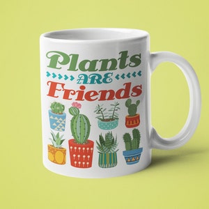 May include: White ceramic mug with a green, blue, and red design featuring the text "Plants are Friends" and various potted cacti and succulents.