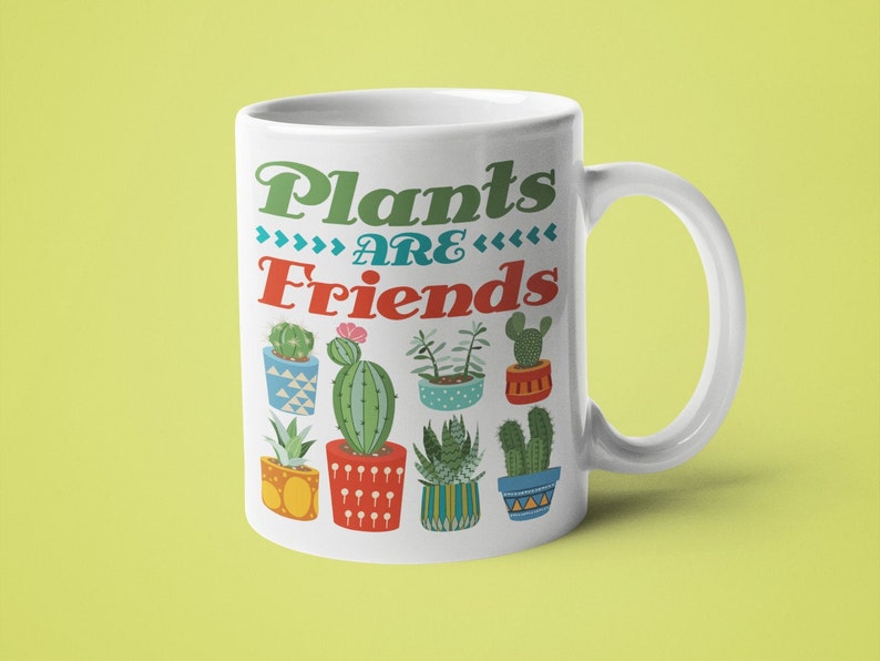 May include: White ceramic mug with a green, blue, and red design featuring the text "Plants are Friends" and various potted cacti and succulents.