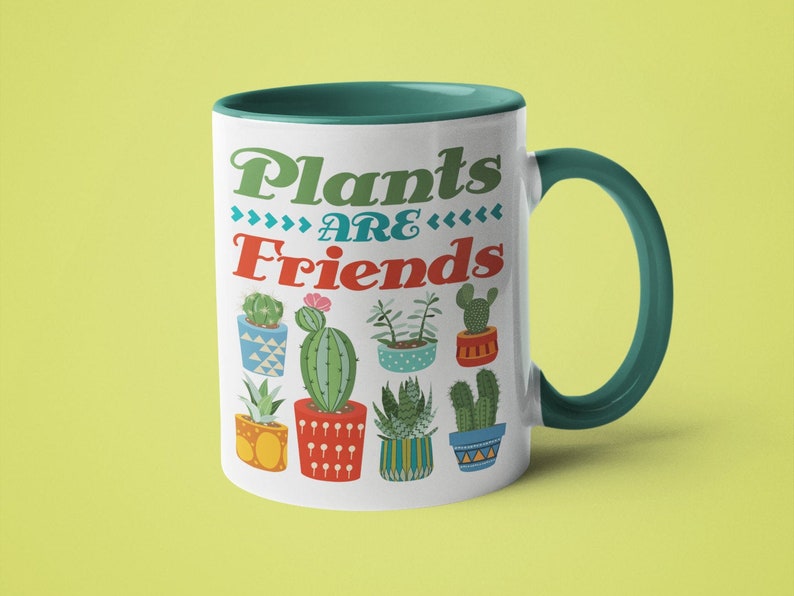 May include: White ceramic mug with a teal rim and handle. The mug features a colorful illustration of potted plants with the text "Plants are Friends" in a retro font.