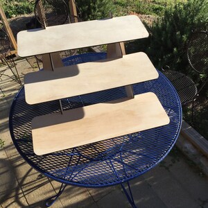 Puede incluir: Un expositor de madera de tres niveles con un acabado de madera natural. El expositor est&aacute; hecho de madera contrachapada y tiene un dise&ntilde;o simple y moderno. Es perfecto para exhibir art&iacute;culos peque&ntilde;os, como joyas, velas u otros art&iacute;culos decorativos.