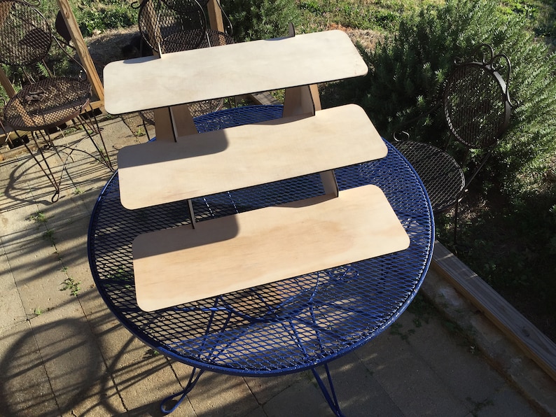 Puede incluir: Un expositor de madera de tres niveles con un acabado de madera natural. El expositor est&aacute; hecho de madera contrachapada y tiene un dise&ntilde;o simple y moderno. Es perfecto para exhibir art&iacute;culos peque&ntilde;os, como joyas, velas u otros art&iacute;culos decorativos.