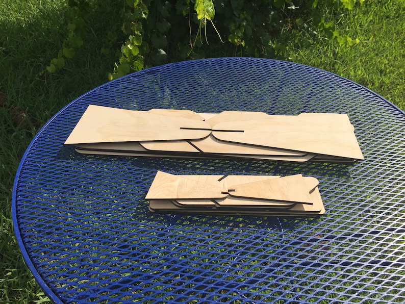 Puede incluir: Dos juegos de piezas de madera, probablemente para un proyecto artesanal, se colocan sobre una mesa de metal azul. El juego m&aacute;s grande tiene cinco piezas, mientras que el juego m&aacute;s peque&ntilde;o tiene cuatro piezas.