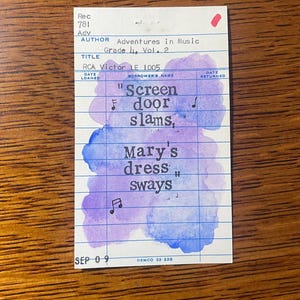 May include: A vintage library card with blue grid lines, featuring watercolor washes of purple and blue. The card has handwritten text including the title "Screen door slams, Mary's dress sways." Musical notes are also present.
