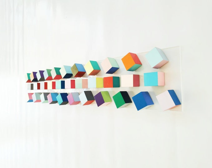 Geometric wall art in happy, joyful colors. 3D art installation on transparent acrylic glass base. Pop art sculpture, block wall sculpture