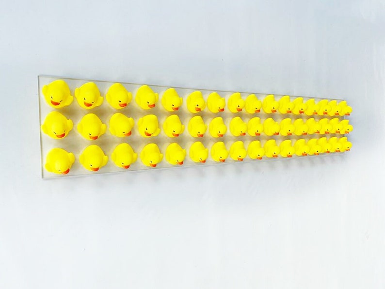 May include: A row of 40 yellow rubber duck toys lined up on a white surface.