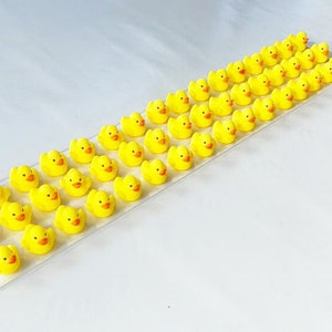 May include: A row of 40 yellow rubber duck figurines arranged on a white surface. The ducks are facing the same direction and are all the same size.