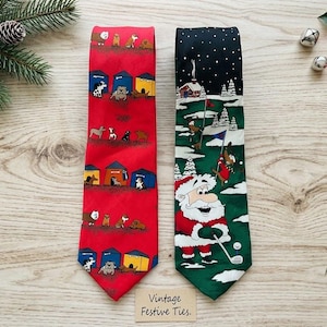 May include: Two neckties displayed side by side. The left tie is red with a repeating pattern of various dog breeds and colorful dog houses. The right tie features a dark sky, snowy landscape, and a cartoon Santa Claus playing golf on a green.