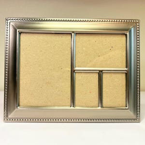 May include: A silver-colored multi-photo frame with four openings. The frame has a beaded border and a rectangular shape. The openings are in various sizes, perfect for displaying multiple photos. The frame is designed to sit on a flat surface.