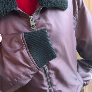 Puede incluir: Una taza de cer&aacute;mica blanca con asa negra y el texto "But First, Coffee" en negrita negra. La taza se encuentra sobre un fondo borroso, sugiriendo un ambiente acogedor.