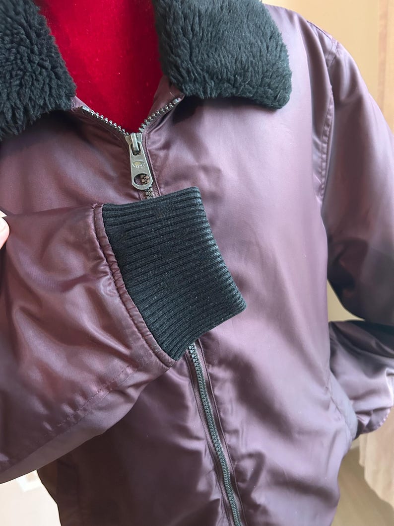 Puede incluir: Una taza de cer&aacute;mica blanca con asa negra y el texto "But First, Coffee" en negrita negra. La taza se encuentra sobre un fondo borroso, sugiriendo un ambiente acogedor.