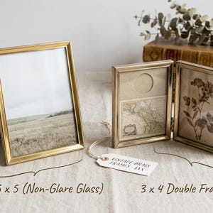 May include: A single brass picture frame with non-glare glass measuring 3.5 x 5 inches and a hinged double brass picture frame measuring 3 x 4 inches. The single frame holds a landscape photo, while the double frame displays a map and a floral print.