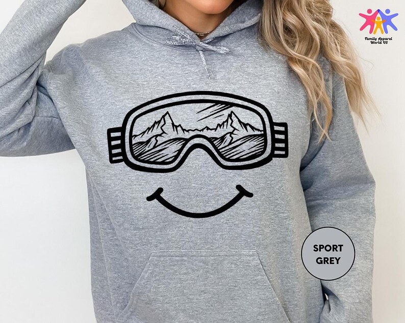 a woman wearing a grey sweatshirt with ski goggles on it