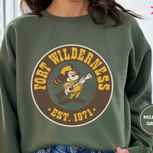 a woman wearing a sweatshirt with a cartoon of a man holding a baseball bat