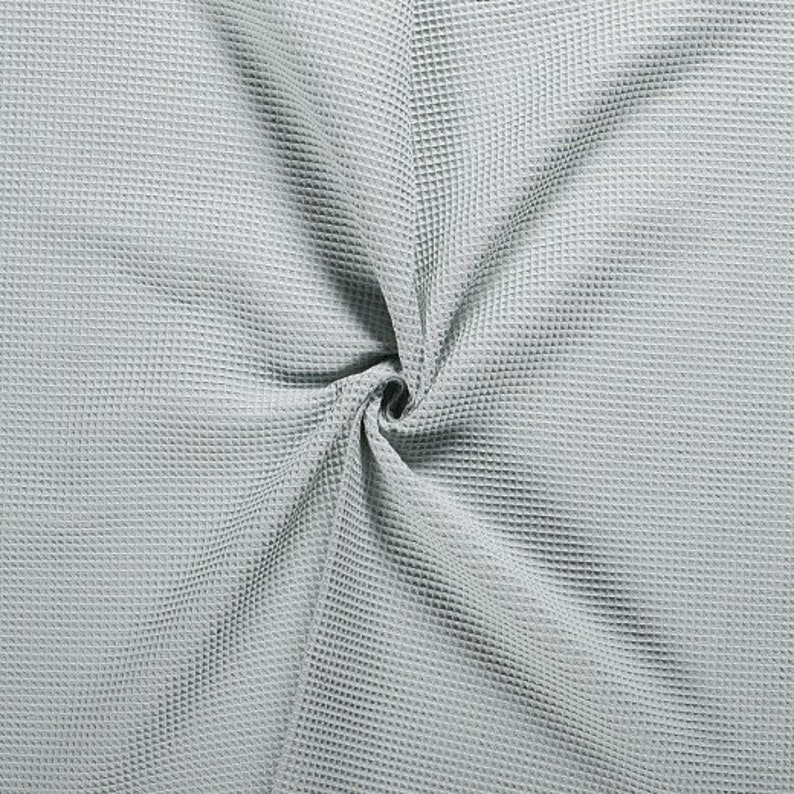 Pode incluir: Um close-up de um tecido de waffle cinza claro. O tecido &eacute; texturizado e tem uma sensa&ccedil;&atilde;o macia e confort&aacute;vel.
