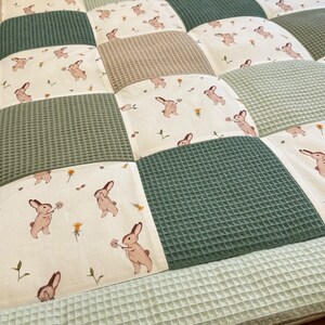 Puede incluir: Una alfombra de juego de patchwork verde y beige con un patr&oacute;n de conejito. La alfombra est&aacute; hecha de tela suave y acolchada, ideal para beb&eacute;s y ni&ntilde;os peque&ntilde;os.