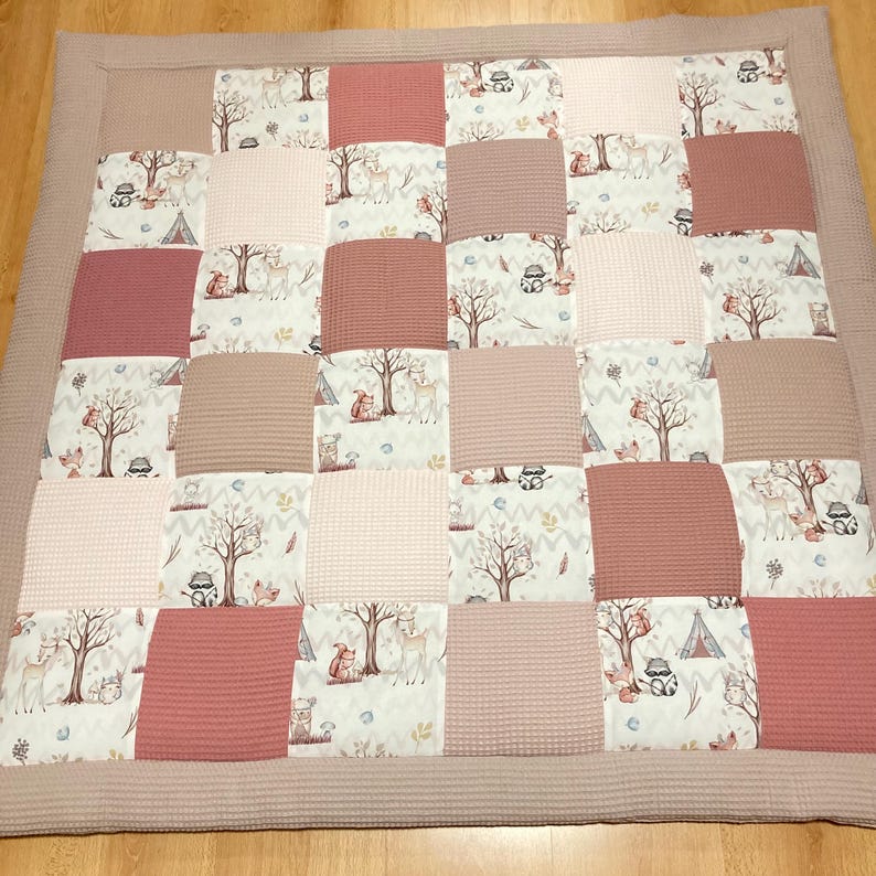 Pode incluir: Um tapete de jogo de patchwork rosa e castanho com estampa de animais da floresta. O tapete &eacute; feito de tecido macio e acolchoado, ideal para beb&ecirc;s e crian&ccedil;as pequenas.