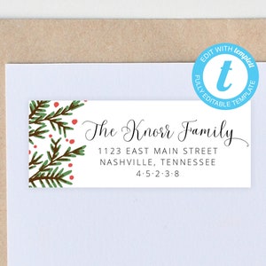 Peut inclure: Une étiquette rectangulaire blanche avec le texte "The Knorr Family" en écriture élégante. L'étiquette comprend une adresse et un code postal. Le coin supérieur gauche présente un motif aquarelle de branches de pin vertes et de baies rouges. Un cercle bleu avec le texte "EDIT WITH templett" est en haut à droite.