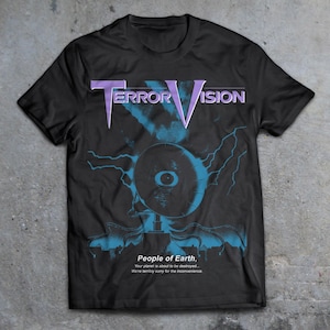 May include: Black t-shirt with a graphic print of a large eye with lightning bolts and the text "TERROR VISION" in purple. The text below the graphic reads "People of Earth, Your planet is about to be destroyed... We're terribly sorry for the inconvenience."