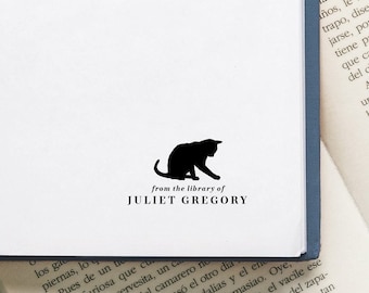 May include: A black silhouette of a cat sitting on a white book with the text "from the library of JULIET GREGORY" printed below.