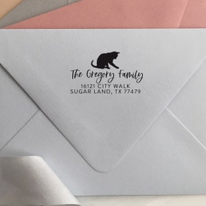 May include: A black cat silhouette with the text "The Gregory Family" and the address "16121 City Walk Sugar Land, TX 77479" on a light blue envelope.