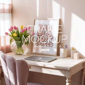 May include: A light-coloured desk with a framed print reading "BIG IDEAS SOFT SPACES". A laptop, pens, and a vase of tulips are on the desk. A pink chair is in front of the desk.