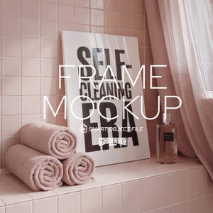 Puede incluir: Escena de baño en tonos rosados, con una obra de arte enmarcada con el texto "SELF CLEANING ERA" y toallas enrolladas. Un frasco de perfume está en la repisa. La escena está suavemente iluminada.
