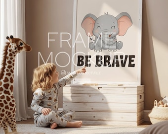 May include: A framed print featuring a cartoon elephant with the text "BE BRAVE". The elephant is gray with pink ears and is smiling. A child in pajamas points at the print. A toy giraffe and a wooden chest are also in the room.