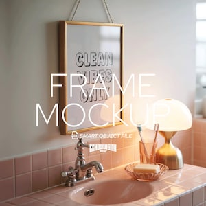 May include: A bathroom scene featuring a gold-framed print with the text "CLEAN VIBES ONLY." The print hangs above a pink sink with a chrome faucet. A gold lamp and a glass with a toothbrush are on the counter. A soap dish is also visible.