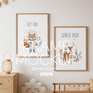 May include: Two framed art prints with wooden frames. One print features a fox in a spacesuit with the text "SLY FOX". The other print shows a deer with the text "GENTLE DEER". The prints are displayed in a nursery setting.