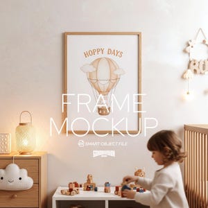 May include: A framed art print with a hot air balloon illustration in a child's room. The print features the words "Hoppy Days" and a hot air balloon design in shades of brown and beige. The frame is made of light wood.