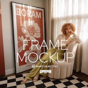 Puede incluir: Un póster grande enmarcado con la palabra "BORAM" en la parte superior y "FRAME MOCKUP" en texto blanco. El póster tiene un fondo coral con diseños florales blancos. El marco es negro y el póster está apoyado contra una pared. La imagen también incluye a una mujer sentada en una silla.