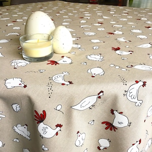 May include: A beige tablecloth with a repeating pattern of white chickens and eggs. The tablecloth is decorated with a red and white chicken design.