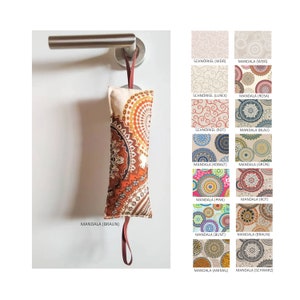 Può includere: Un fermaporta rettangolare decorativo con un motivo mandala marrone, appeso a una maniglia. Il fermaporta ha un anello per appenderlo ed è realizzato in tessuto. L'immagine mostra anche vari campioni di tessuto con diversi disegni mandala.