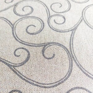 May include: A close-up of a beige fabric with a repeating pattern of grey swirls.