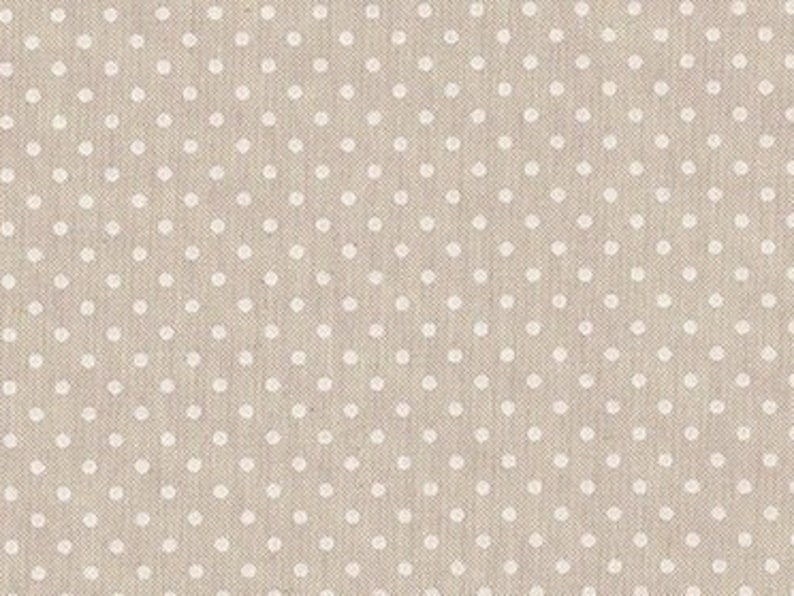 May include: A beige fabric with a white polka dot pattern. The fabric has a subtle texture.