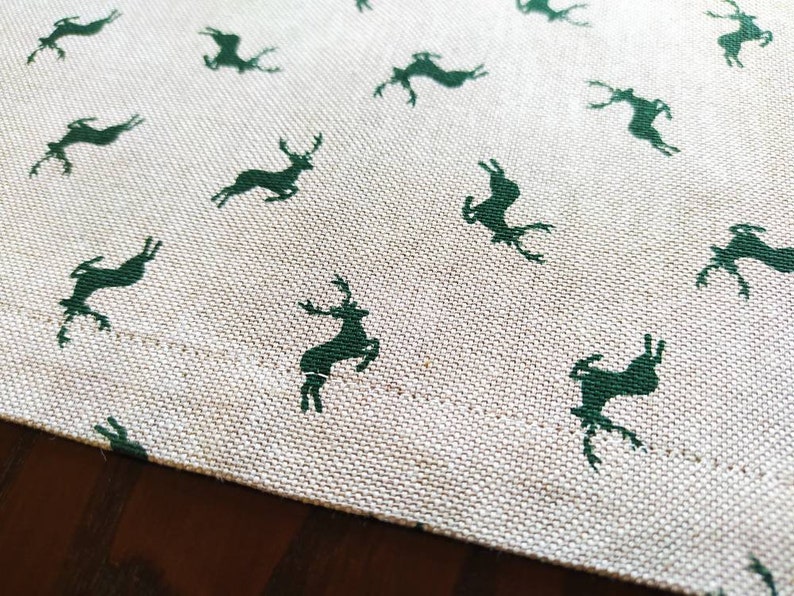 May include: A white tablecloth with a repeating pattern of dark green deer silhouettes.