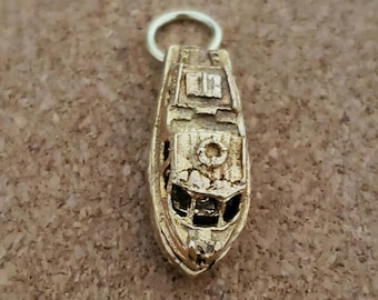 May include: A gold-colored charm in the shape of a boat. The boat has a small window and a detailed design.