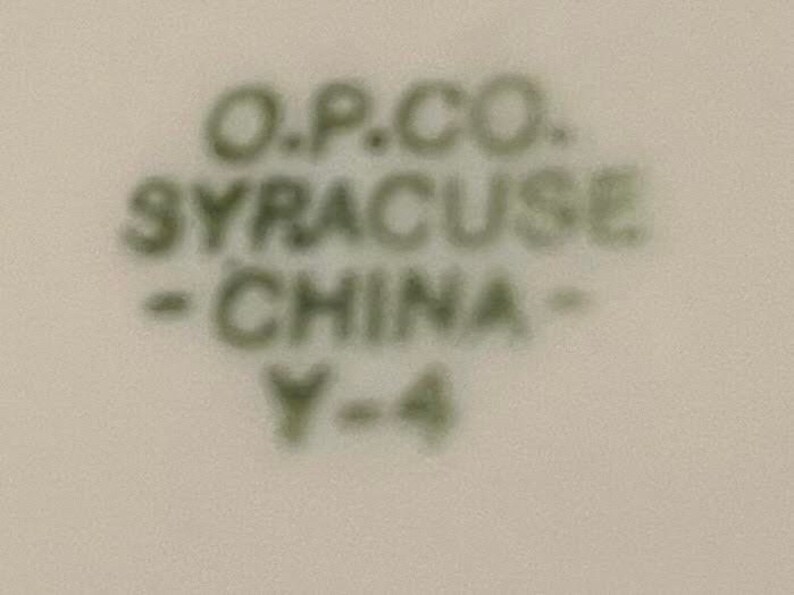 May include: Close-up of a green and white ceramic mark that reads "O.P.CO. SYRACUSE - CHINA - Y-4".